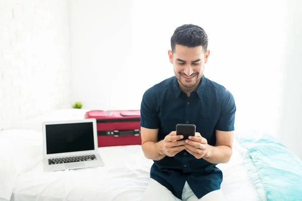 Snygg Man Leende När Använder Smartphone Med Laptop Och Bagage — Stockfoto