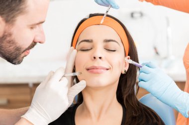 Kadın yüzüne gözleri kapalı enjekte kozmetologlar elleri