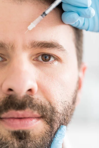 Determined man receiving anti wrinkle injections for better complexion