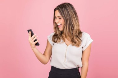 Beklenmedik haberlerle mutlu bir kadın akıllı telefonda parlıyor.
