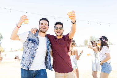 Yaz müzik festivalinde kollarını etrafında ayakta iken bira tezahürat yakışıklı erkeklerin Portresi