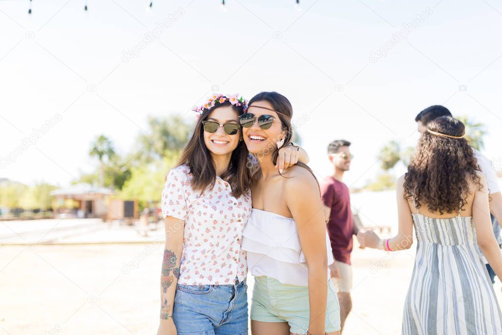 Portrait of gorgeous women wearing sunglasses while standing around at music festival