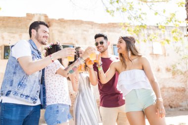 Neşeli genç arkadaşlar yaz partisi kutlamaları sırasında bira kadehleri toasting