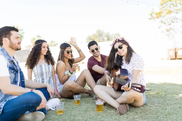 Amigos Sorridentes Ouvindo Mulher Tocando Guitarra Enquanto Desfruta Bebidas Festival — Fotografia de Stock