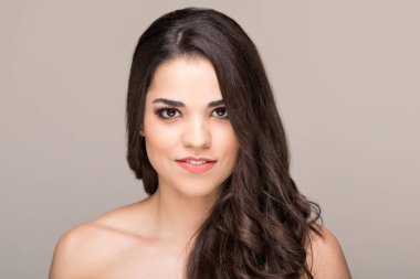 Çıplak omuzları düz arka plan karşı gülümseyen Muhteşem Latin esmer