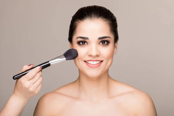 Artista Aplicando Blush Rosto Modelo Com Escova Contra Fundo Liso — Fotografia de Stock