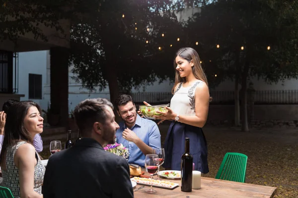 若い女性は裏庭のテーブルで友人に夕食を提供 — ストック写真