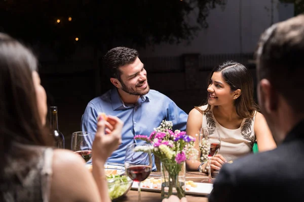 Romantic couple having dinner outdoors with friends