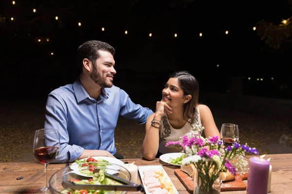 微笑的伙伴在爱看着对方 而晚上在餐厅吃饭 — 图库照片