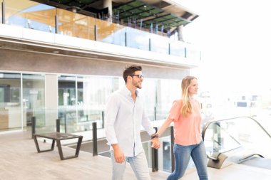 Alışveriş merkezinde yürürken el ele tutuşan genç çift