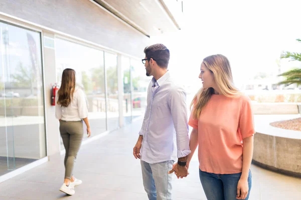Caucasian man paying attention to other female while roaming in shopping mall with girlfriend
