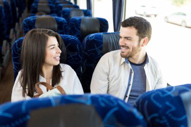Otobüste seyahat ederken birbirlerine bakan gülümseyen arkadaşlar