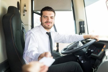 Bilet satarken üniforma giyen kendinden emin genç otobüs şoförü