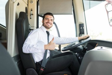 Seyahat otobüsünde otururken başparmağını gösteren otobüs şoförünün portresi