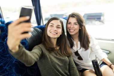 Tur otobüsünde kendi portresini çekerken gülümseyen güzel genç kadınlar