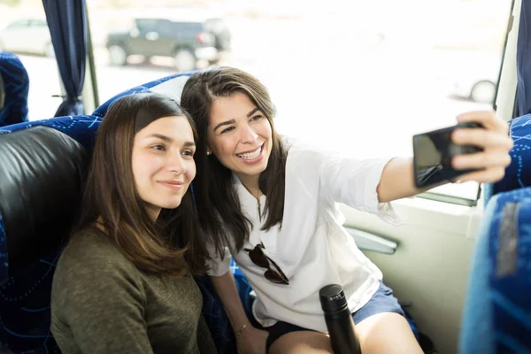 西班牙裔妇女采取自拍与朋友使用智能手机在公共汽车上 — 图库照片