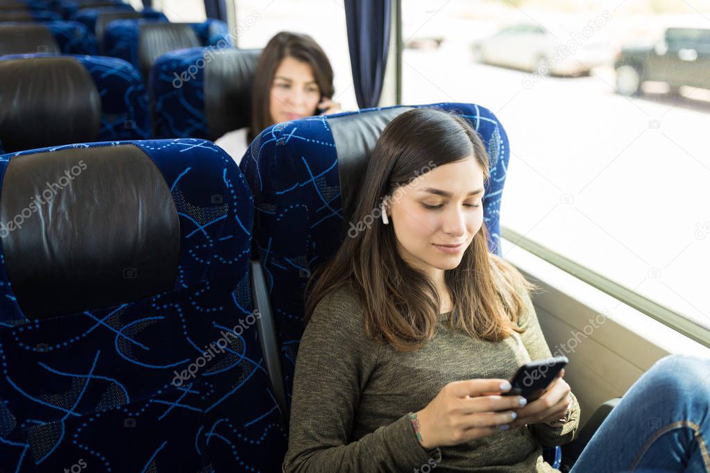 Brunette passenger listening music on smartphone while traveling in bus