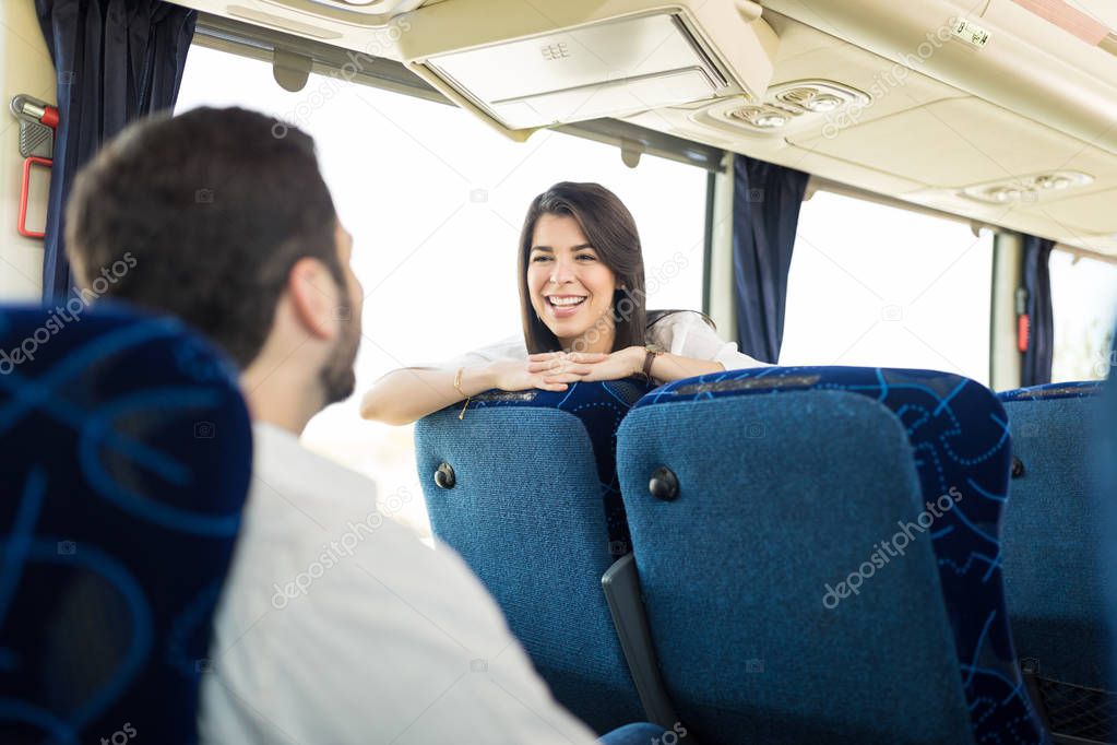 Happy woman talking to man while traveling in bus