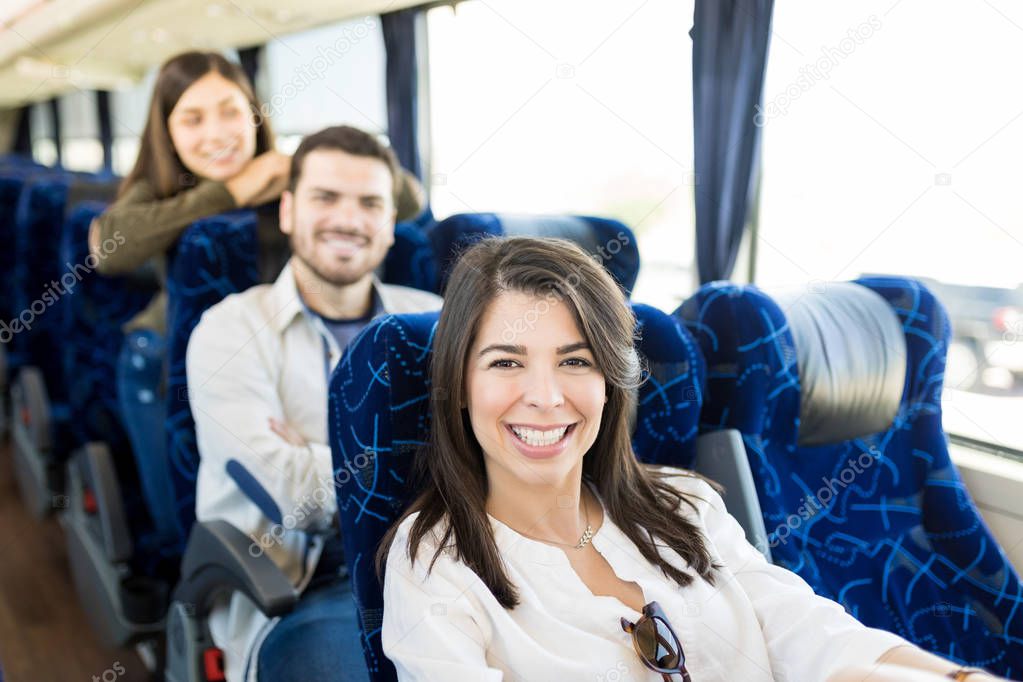 Happy Hispanic man with female friends traveling in bus