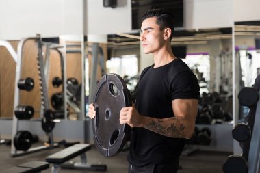 Motive spor hocası sağlık kulübünde ayakta iken ağırlık disk kaldırma