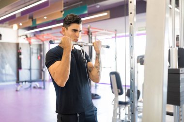 Genç adam fitness kulübünde kas geliştirme hareketleri yapıyor.