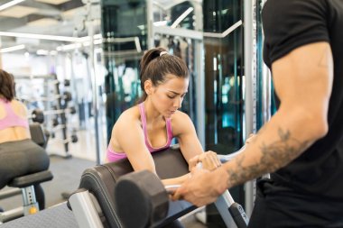 Sağlık kulübünde kişisel antrenör yardımı ile odaklanmış genç kadın eğitimi