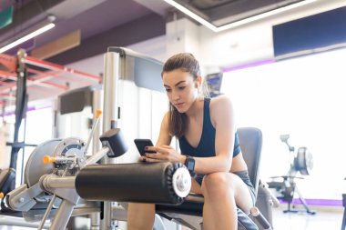 Fitness salonunda egzersiz sonra akıllı telefonda mesajlaşma iyi görünümlü kadın
