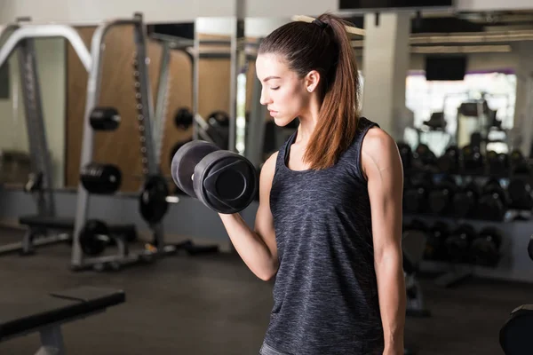 强壮的年轻女子在健身房使用举重来锻炼肌肉 — 图库照片