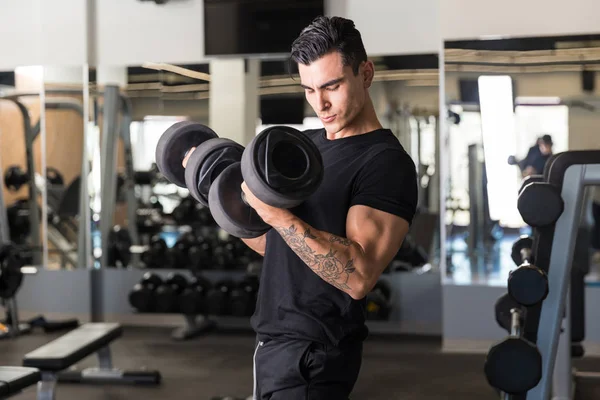 Dedicated Latin man in sportswear working out in gymnasium