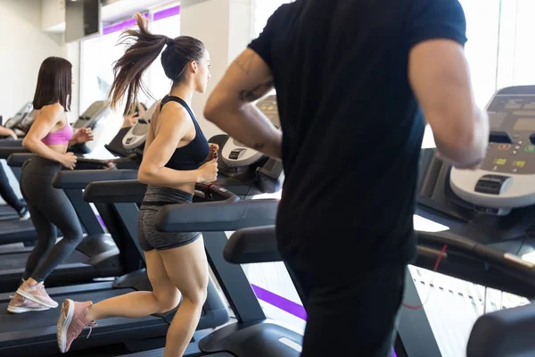 男性和女性朋友在现代健身房的跑步机上锻炼 — 图库照片
