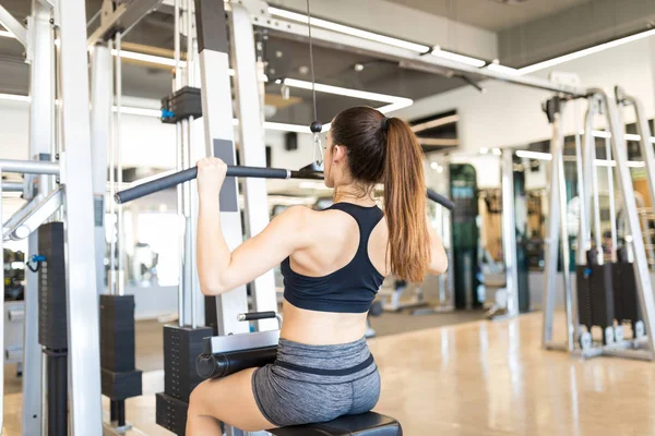 Female athlete building upper body strength with exercise machine in gymnasium