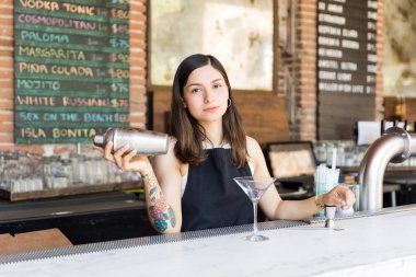 Kendine güvenen Latin barmaid restoranda bar tezgahında alkollü içki karıştırma