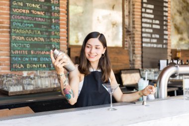 Gülümseyen kadın mixologist bar tezgahında shaker kokteyl hazırlanıyor