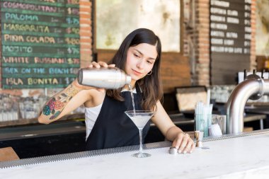 Profesyonel kadın barmen bar tezgahında cam içine kokteyl dökme