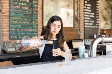 Barmaid restoranda bar tezgahında kokteyl hazırlarken jigger likör dökme