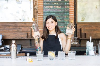 Barda kokteyl yapan alkollü içecekler ile gülümseyen barmaid