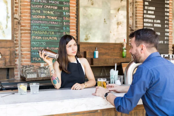 顾客在酒吧柜台喝啤酒时与女调酒师交谈 — 图库照片