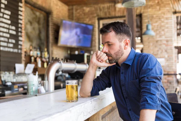 Thoughtful male customer having drink while sitting at bar counter
