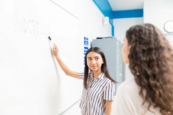十几岁的女孩在学校与同学讨论白板上的方程式 — 图库照片