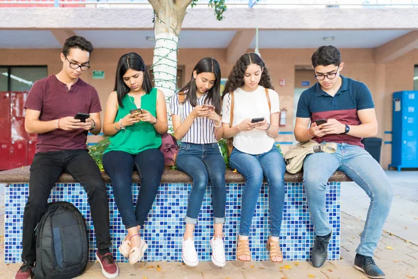 Comprimento Total Amigos Usando Telefones Celulares Enquanto Estavam Sentados Campus — Fotografia de Stock