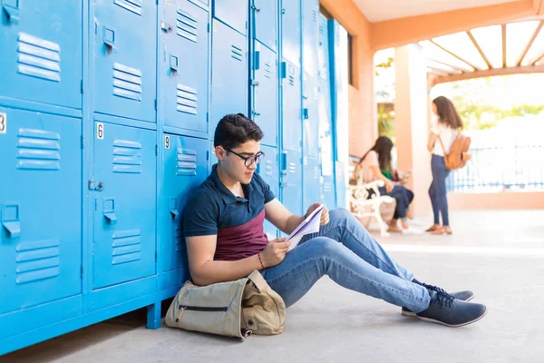大学のキャンパスに座っている間 深刻なラテンの男子学生読書本 — ストック写真