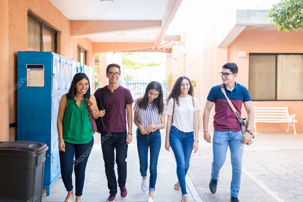 Happy friends talking while walking in hallway at university