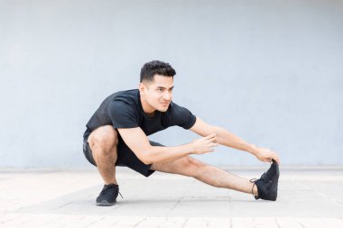 Onun Koşmadan önce egzersiz germe yapıyor atletik adam tam uzunluğu