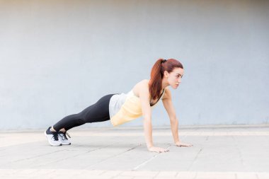 Şehirde duvara kaldırım üzerinde Push-up yapıyor sportif kadın Runner