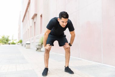 Şehirde egzersiz sonrası rahatlatıcı yorgun erkek koşucu