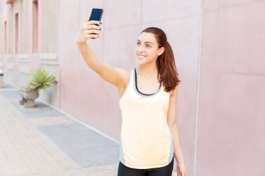 Şehirde akıllı telefonda selfie çeken güler yüzlü kadın