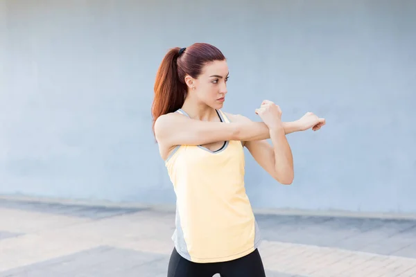 专注的女人在运动服装伸展手保持健康 — 图库照片