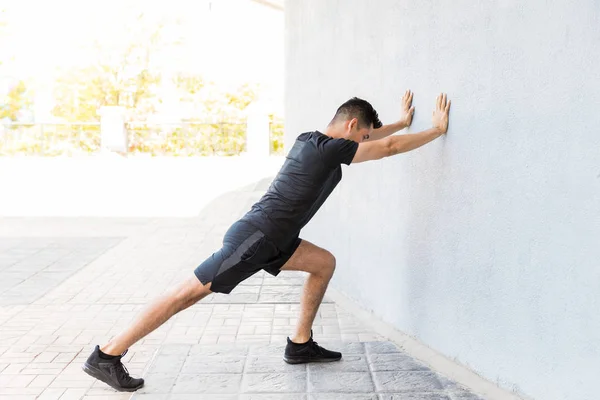 Determined Young Latin Man Stretching Calf While Leaning Wall — Stock Photo, Image