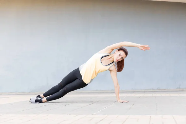 Charming fit runner making eye contact while balancing on one arm