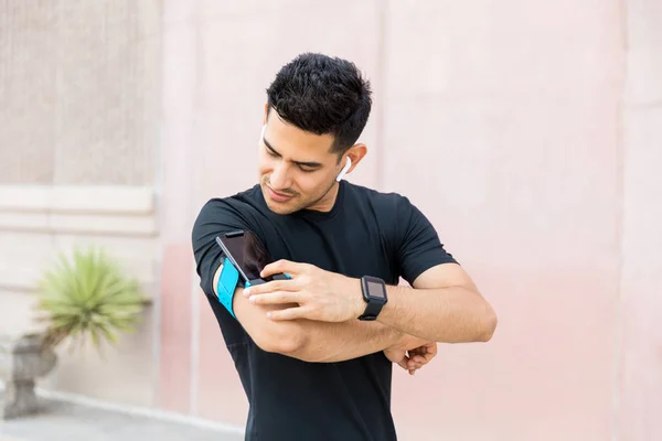 Biegacz Dotykając Wyświetlacza Ekran Dotykowy Opaskę Telefonem Komórkowym Słuchania Muzyki — Zdjęcie stockowe